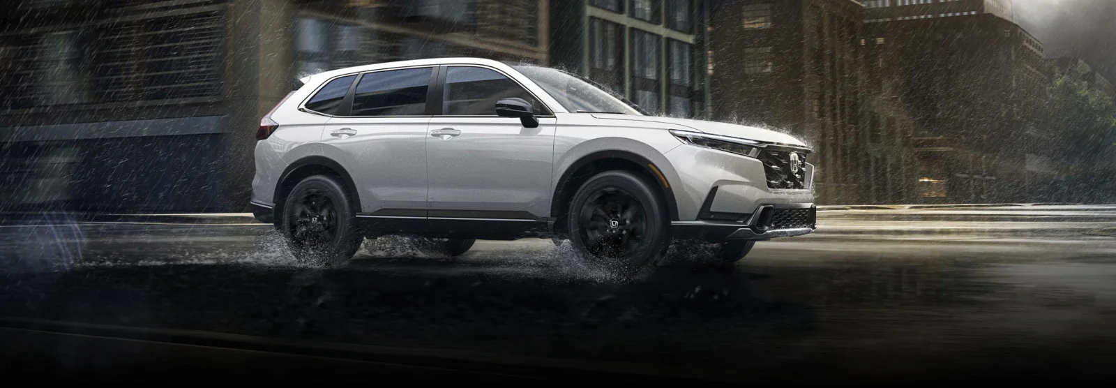 A white CR-V driving through a rain-soaked city street.