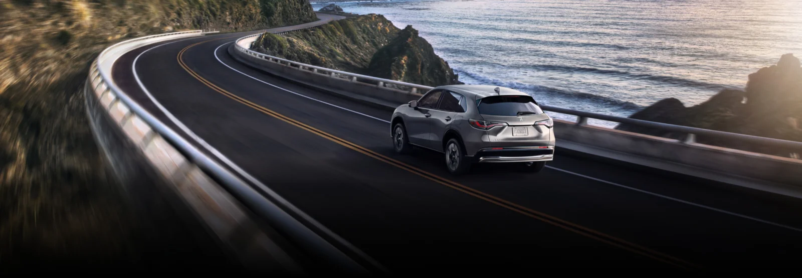 A silver HR-V driving along a winding coastal highway.